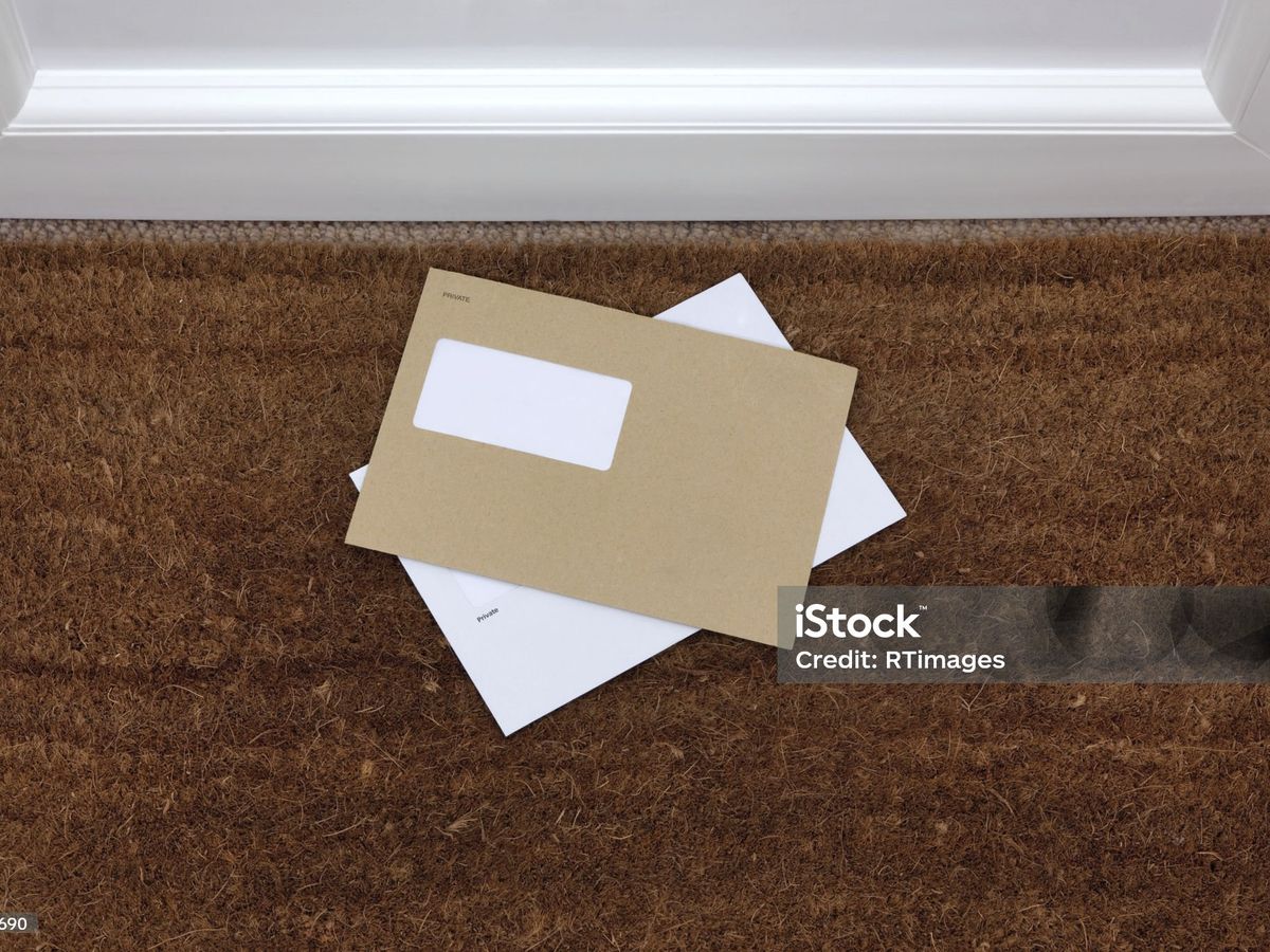 Two letters on a doormat just inside a front door